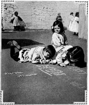 Children writing outside with chalk on the ground