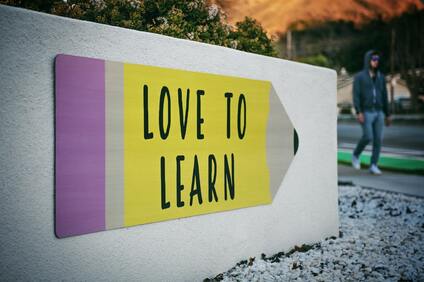 Sign in the shape of a pencil that says love to learn